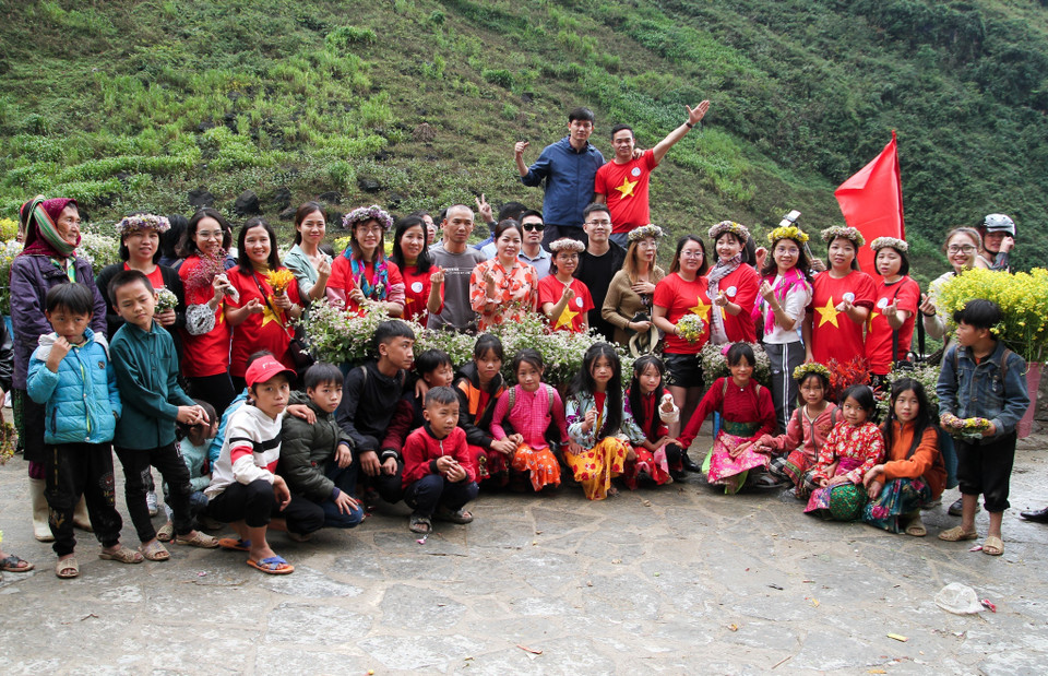 Khách du lịch chụp ảnh cùng các em nhỏ vùng cao tại điểm "check in" Dốc Thẩm Mã. (Ảnh: Nam Thái/TTXVN)