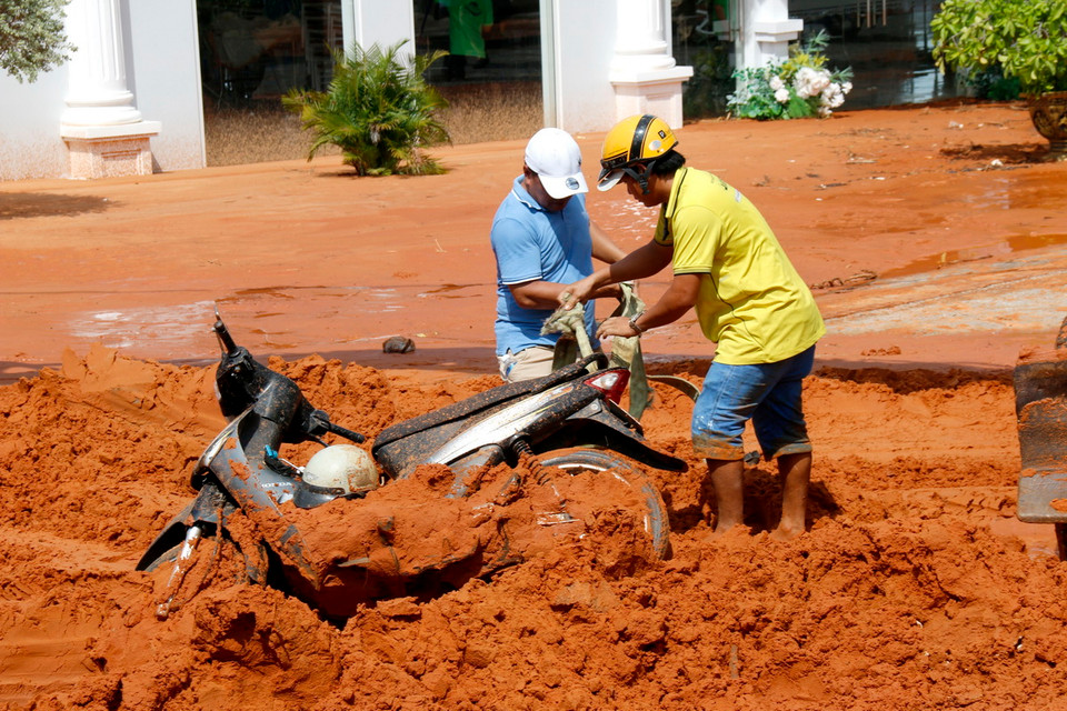 Người dân di chuyển xe máy bị cát vùi lấp ra ngoài. (Ảnh: Nguyễn Thanh/TTXVN)