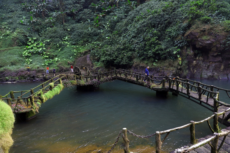 Cây cầu nhỏ nối liền hai bờ dưới chân thác quanh năm rêu phủ. (Ảnh: Huy Hùng/TTXVN)