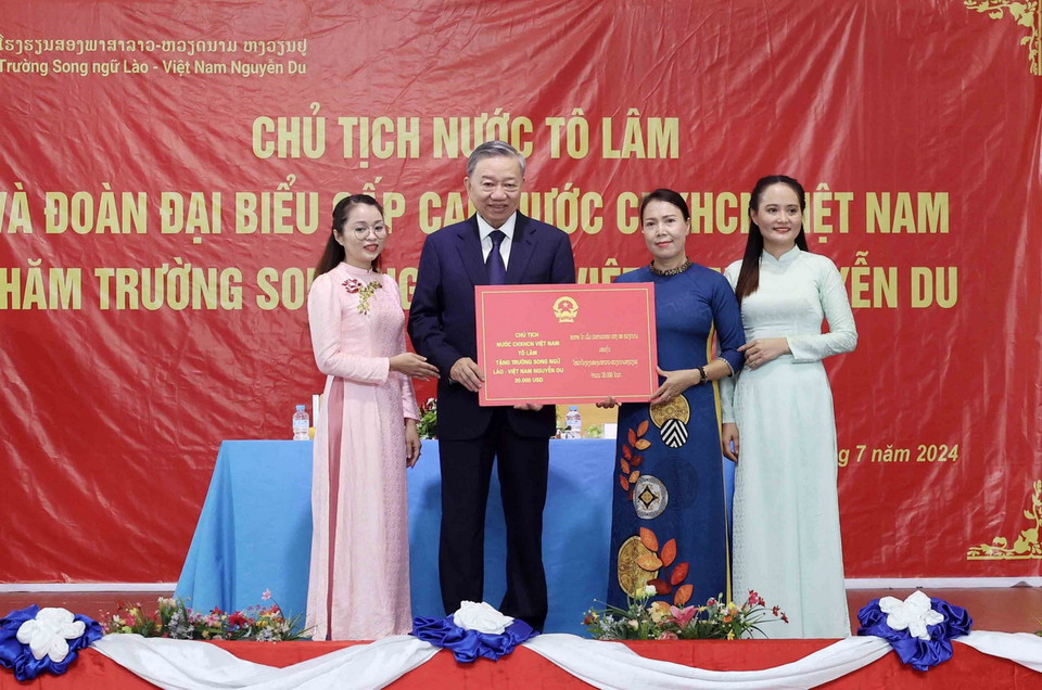Chủ tịch nước Tô Lâm tặng quà cho Trường song ngữ Lào-Việt Nam. (Ảnh: Nhan Sáng/TTXVN)