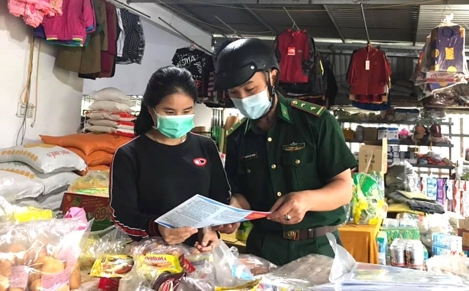 Chiến sỹ biên phòng Quảng Trị phát tờ rơi đến người dân, tuyên truyền phòng, chống dịch COVID-19. (Ảnh: TTXVN phát)