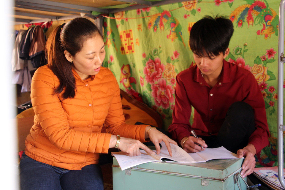 Cô giáo Nguyễn Thùy Dung, trường Trung học cơ sở Mường Khiêng, giúp học sinh được đỡ đầu làm bài tập. (Ảnh: Hữu Quyết/TTXVN)