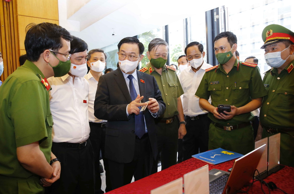 Chủ tịch Quốc hội Vương Đình Huệ nghe giới thiệu về tính năng hiện đại của căn cước công dân có gắn chíp điện tử. (Ảnh: Doãn Tấn/TTXVN)