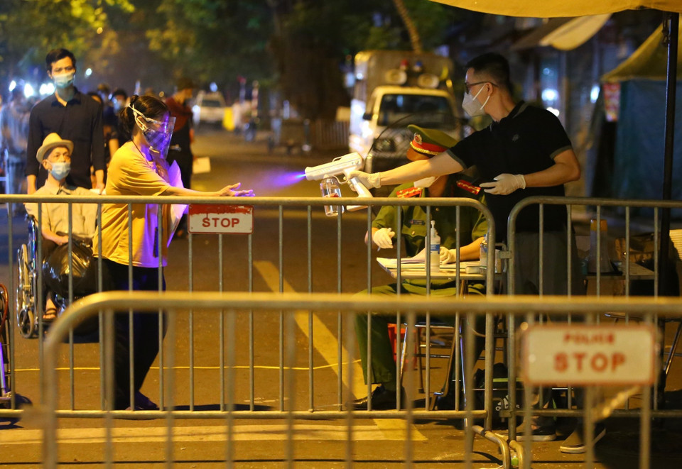 Xịt sát khuẩn tay với những người chuẩn bị rời khỏi khu vực phong tỏa. (Ảnh: Hoàng Hiếu/TTXVN)