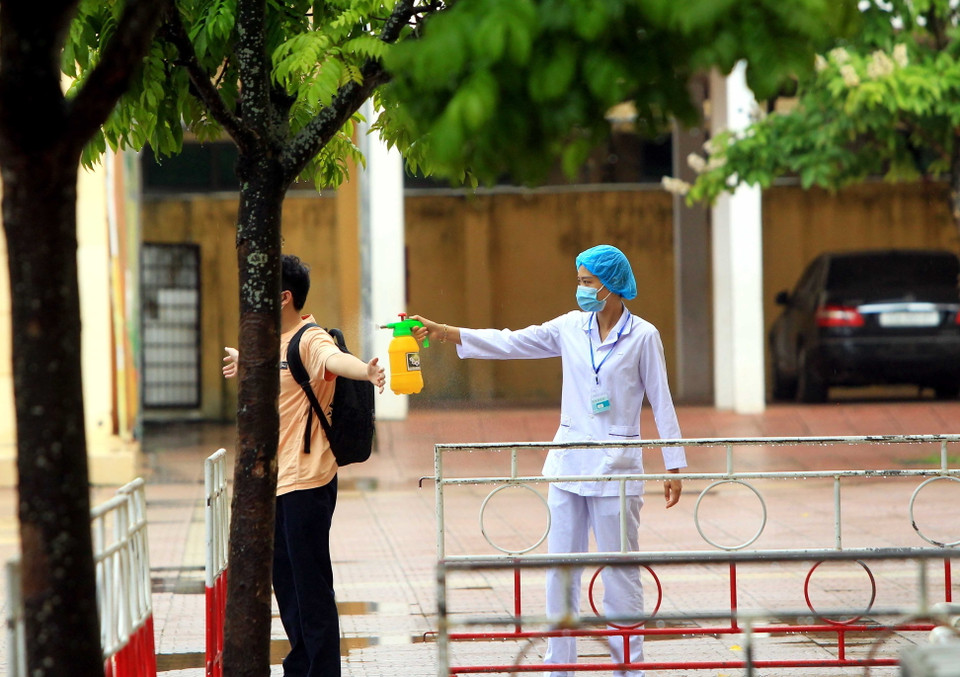 Các thí sinh thuộc diện F2 tuân thủ các biện pháp chống dịch trước khi vào phòng thi. (Ảnh: An Đăng/TTXVN)