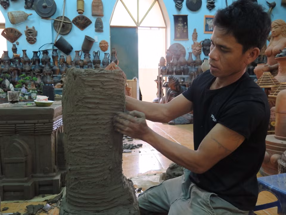Người Chăm không sử dụng men mà dùng vải nhúng nước để chà láng, dùng nhựa cây rừng để tăng thêm sắc màu của gốm. Trong ảnh: Tạo hình phần chân cho bức tượng thần 4 mặt cao 1m8 bằng gốm Bàu Trúc. (Ảnh: Minh Hưng/TTXVN)