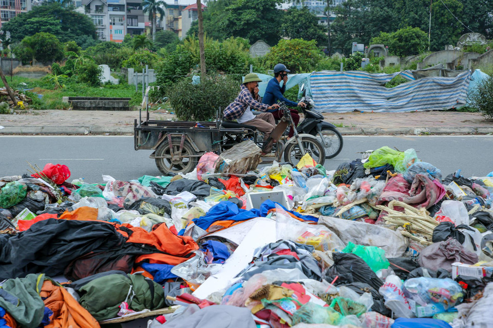 Dù đã bịt kín bằng khẩu trang, nhưng 2 người trong ảnh vẫn tỏ ra khó chịu vì mùi hôi bốc lên từ bãi rác. (Ảnh: Minh Sơn/Vietnam+)