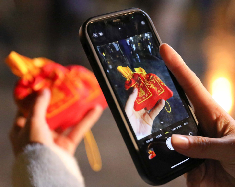 Chụp lại ngay túi lương vừa nhận được để chia sẻ với người thân và bạn bè. (Ảnh: Thanh Tùng/TTXVN)