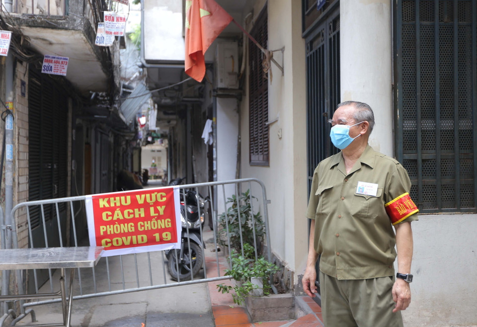 Lực lượng dân phòng hỗ trợ đảm bảo việc cách ly lối vào khu nhà E2. (Ảnh: Hoàng Hiếu/TTXVN)