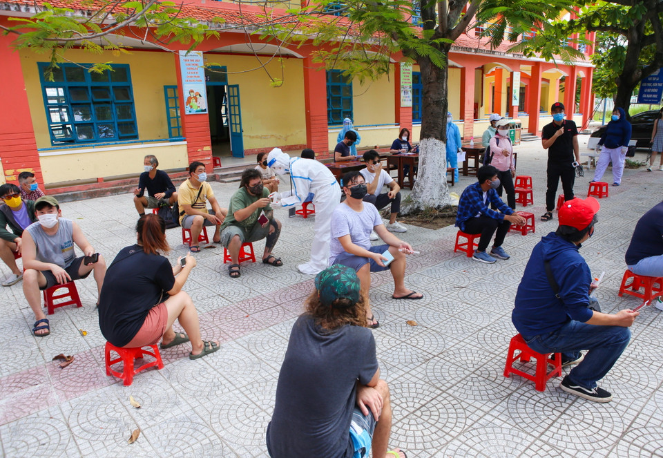 Người nước ngoài được ngồi giãn cách theo quy định phòng dịch trước khi lấy mẫu xét nghiệm tại quận Sơn Trà (Đà Nẵng). (Ảnh: Trần Lê Lâm/TTXVN)