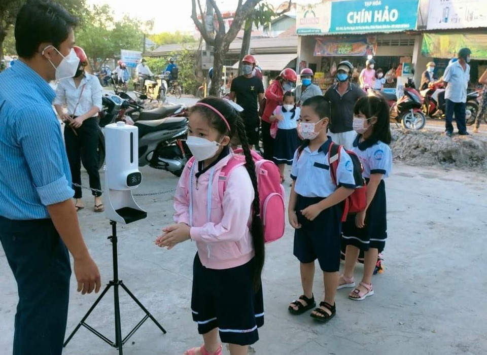 Các học sinh được hướng dẫn rửa tay, kiểm tra thân nhiệt trước khi vào trường. (Ảnh: TTXVN phát)