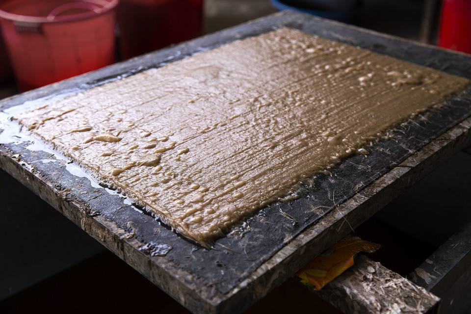 Từng lớp bột giấy mỏng tách khỏi khuôn liềm theo từng lớp chồng lên nhau, khoảng 40-50 tờ, sau đó chuyển sang công đoạn ép giấy cho hết nước rồi tách giấy đem phơi khô. (Ảnh: Trọng Đạt/TTXVN)