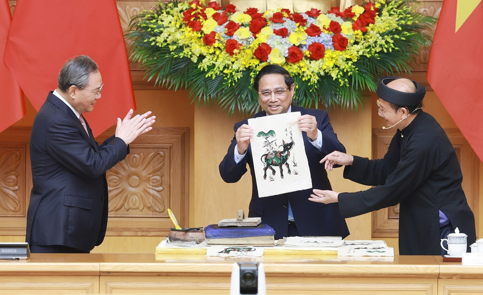 Thủ tướng Phạm Minh Chính và Thủ tướng Trung Quốc Lý Cường cùng làm tranh dân gian Đông Hồ. (Ảnh: Dương Giang/TTXVN)