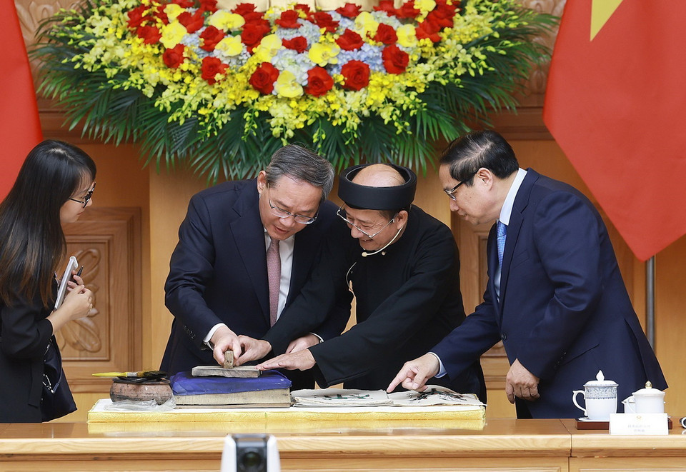 Thủ tướng Phạm Minh Chính và Thủ tướng Trung Quốc Lý Cường cùng làm tranh dân gian Đông Hồ. (Ảnh: Dương Giang/TTXVN)