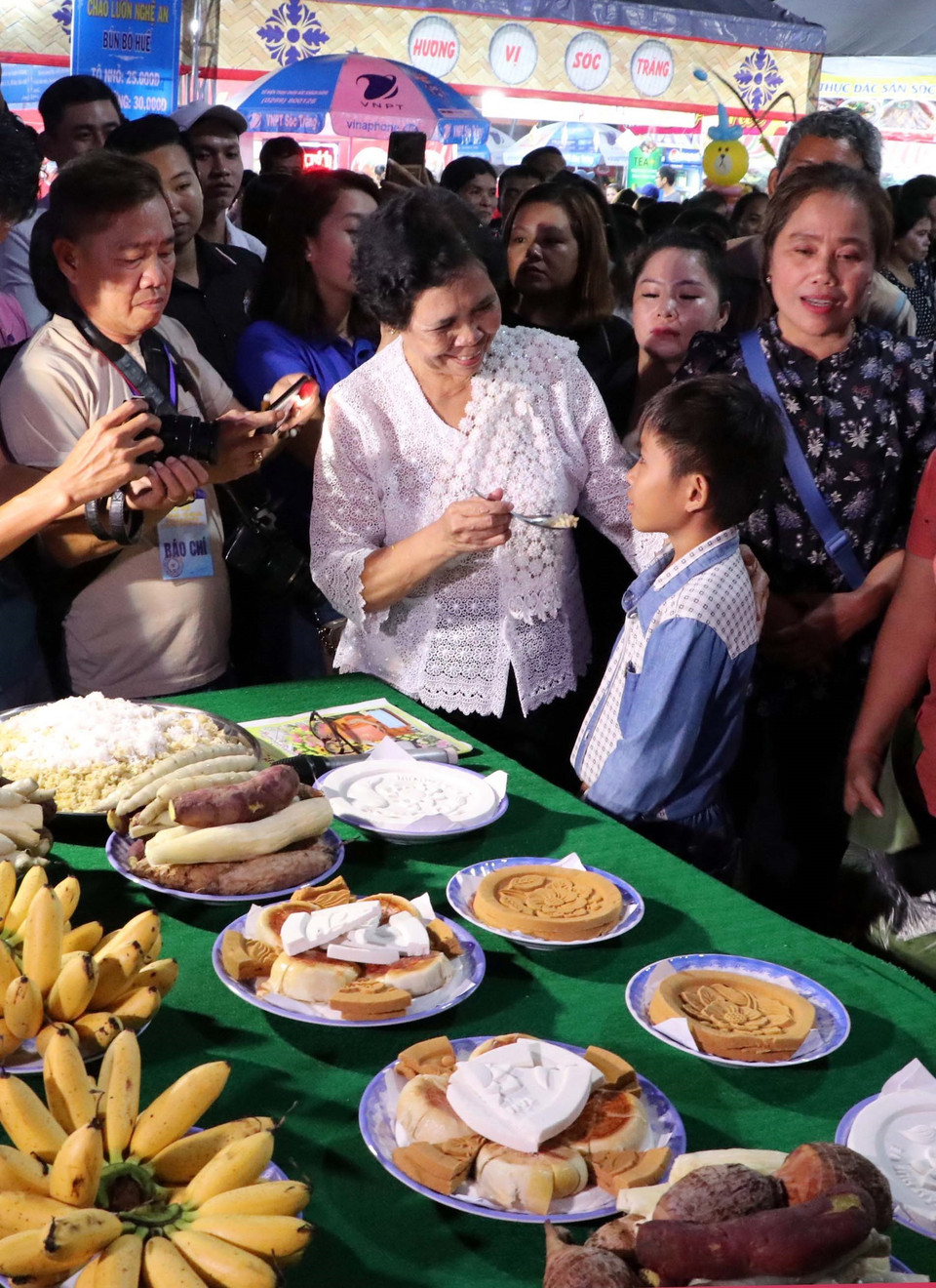 Phong tục Đút cốm dẹp cho trẻ em và hỏi lớn lên sẽ làm nghề gì. (Ảnh: Trung Hiếu/TTXVN)