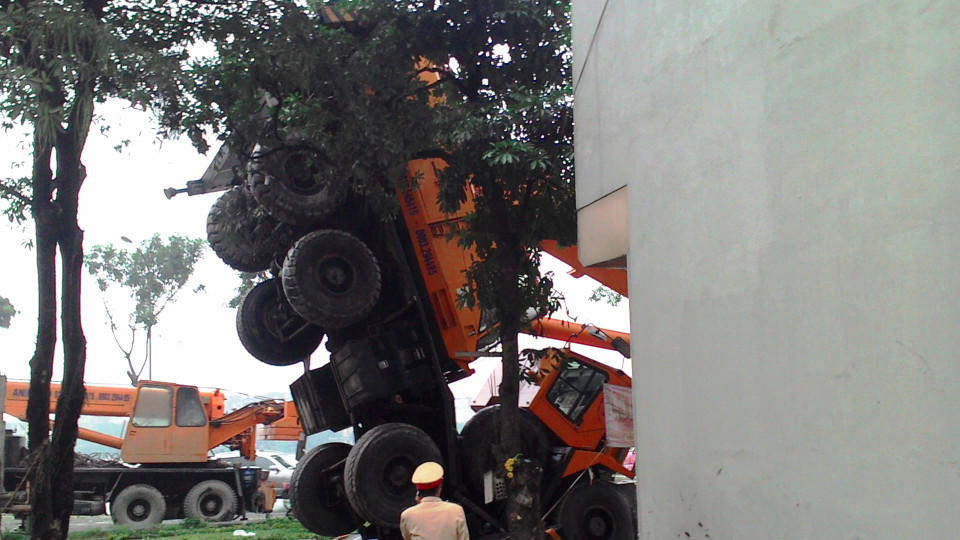 Trong khi vương thử cẩu, phần thân xe đã bị lật đứng do tay cẩu sập xuống. Toàn bộ bánh xe dựng đứng vuông góc so với mặt đất. (Ảnh: Sơn Bách/Vietnam+)
