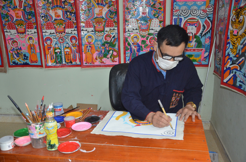 Ông Triệu Hùng Cường đang miệt mài vẽ những bộ tranh thờ với sự cẩn trọng, tỷ mỷ, và sự thấu hiểu về giá trị văn hóa của dân tộc mình qua mỗi bộ tranh. (Ảnh: Hoa Mai/TTXVN)