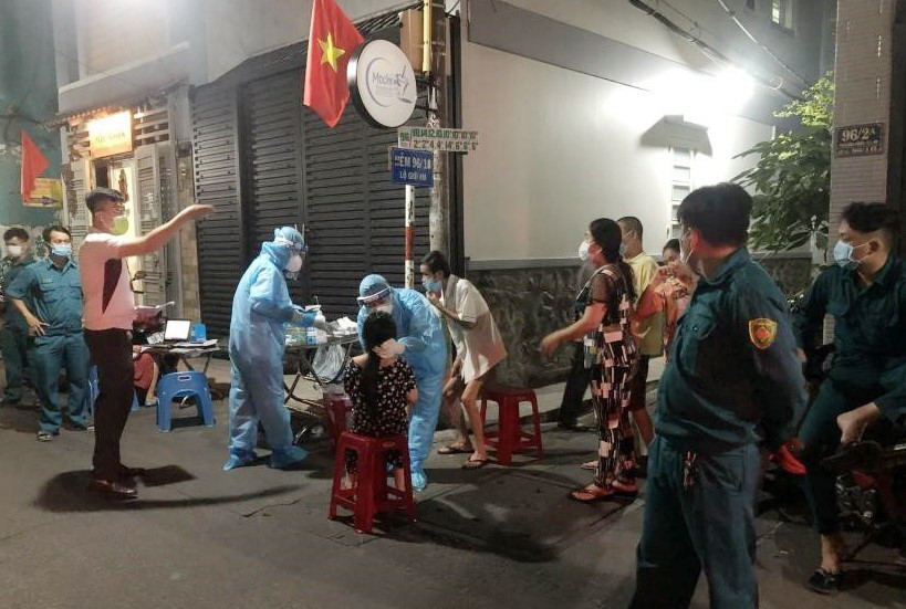 Nhân viên Trung tâm Y tế quận Phú Nhận lấy mẫu xét nghiệm cho người dân khu vực hẻm 96, đường Phan Đình Phùng tối 30 Tết. (Ảnh: TTXVN phát)