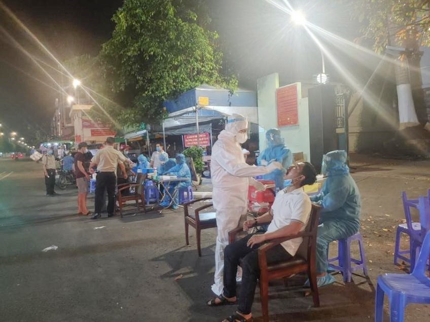 Nhân viên Trung tâm Y tế Thành phố Thủ Đức, Thành phố Hồ Chí Minh lấy mẫu xét nghiệm cho tiểu thương chợ đầu mối Thủ Đức tối Mùng 1 Tết. (Ảnh: TTXVN phát)