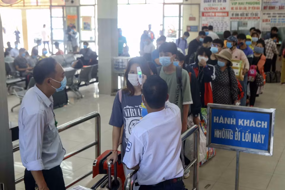 Nhân viên kiểm tra thân nhiệt hành khách tại bến xe Mỹ Đình. (Ảnh: Tuấn Đức/TTXVN)