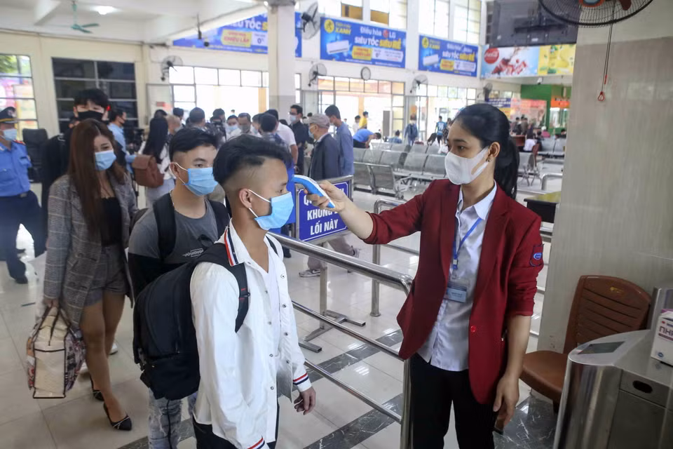Nhân viên kiểm tra thân nhiệt hành khách tại bến xe Mỹ Đình. (Ảnh: Tuấn Đức/TTXVN)