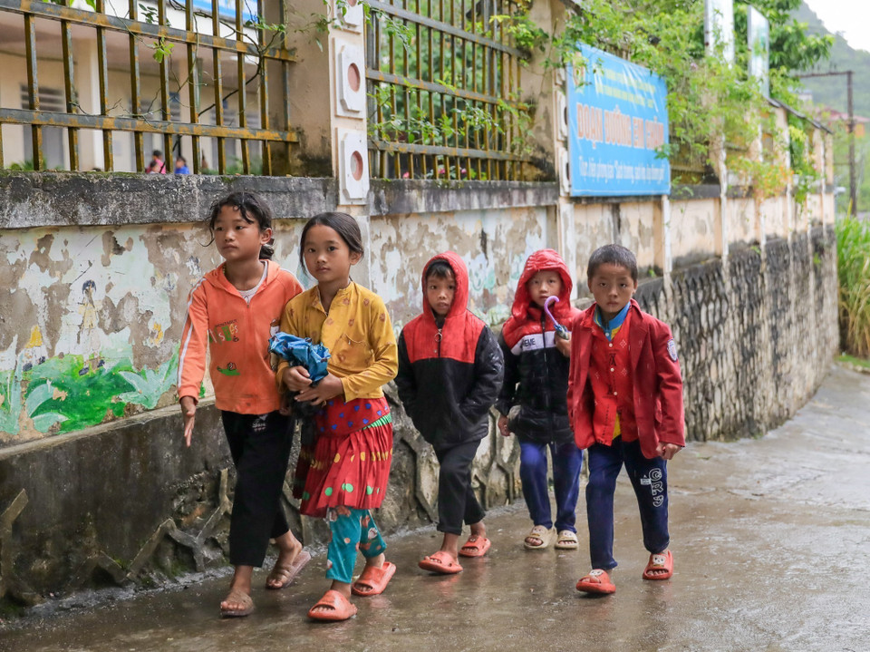Mưa lớn kéo dài khiến việc tới trường của học sinh Trường Phổ thông dân tộc bán trú Tiểu học Cán Chu Phìn (Mèo Vạc) khó khăn, vất vả hơn. (Ảnh: Nam Thái/TTXVN)