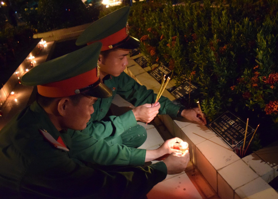 Chiến sỹ lực lượng vũ trang thắp hương tưởng niệm trên phần mộ liệt sỹ tại Nghĩa trang Liệt sỹ tỉnh Đồng Tháp. (Ảnh: Chương Đài/TTXVN)