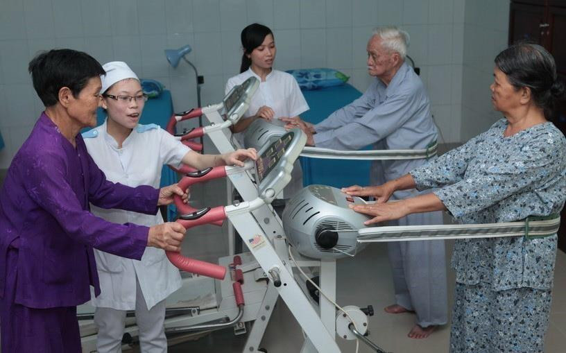 Nhân viên Trung tâm Chăm sóc người có công với cách mạng tỉnh Bình Định hướng dẫn người có công tập phục hồi chức năng. (Ảnh: Anh Tuấn/TTXVN)