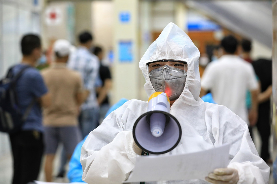 Nhân viên Trung tâm Y tế quận Đống Đa dùng loa đọc tên từng người vào lấy mẫu xét nghiệm. (Ảnh: Thành Đạt/TTXVN)