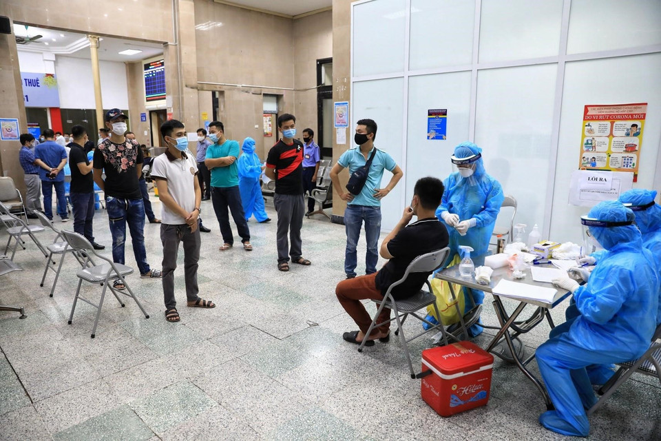 Cán bộ, công nhân viên làm việc tại Ga Hà Nội xếp hàng lấy mẫu xét nghiệm đảm bảo khoảng cách cần thiết. (Ảnh: Thành Đạt/TTXVN)