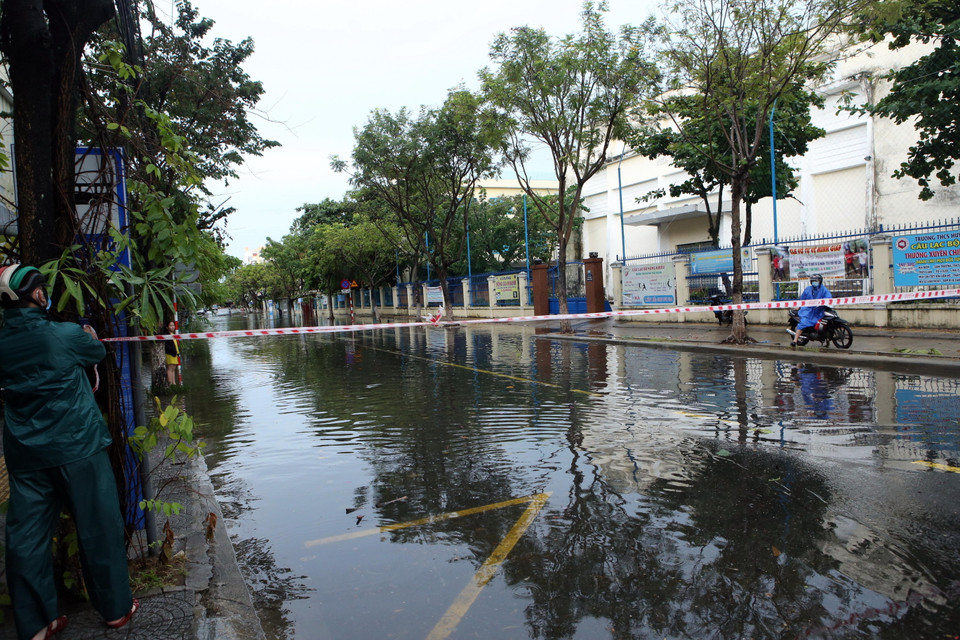 Lực lượng chức năng giăng dây cảnh báo tại khu vực ngập nước trên đường Hà Huy Tập. (Ảnh: Trần Lê Lâm/TTXVN)