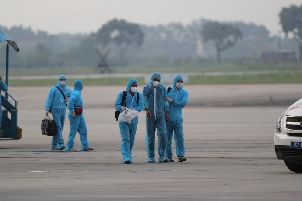 Nhân viên y tế hỗ trợ công dân (giữa) ra xe ô tô về khu cách ly y tế. (Ảnh: Thành Đạt/TTXVN)