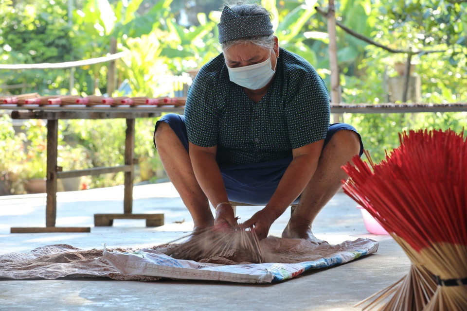 Khi lăn hương, người làm dùng cán hương nhúng vào xô nước, sau đó đem ra lăn qua lăn lại trên lớp bột khô đã được trộn sẵn, rồi lại nhúng nhanh vào xô nước mang ra tiếp tục lăn đến khi nào đạt tiêu chuẩn thì thôi, đây là công đoạn quyết định mẫu mã và cả chất lượng của nén hương. (Ảnh: Minh Quyết/TTXVN)