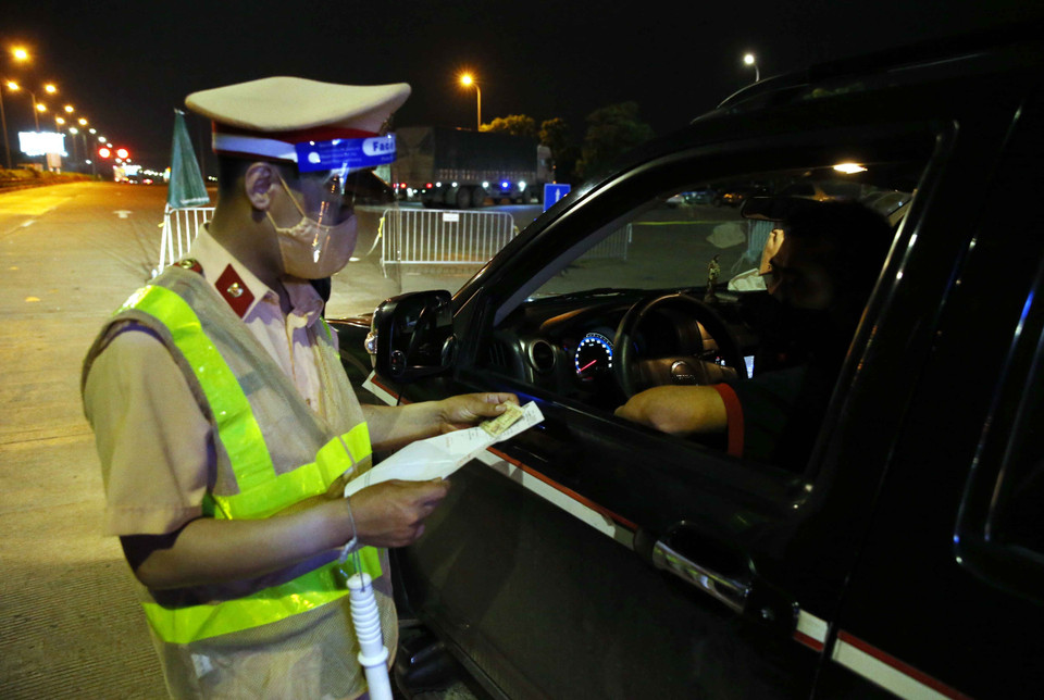 Cán bộ Đội cảnh sát giao thông số 14 kiểm tra giấy tờ các chủ phương tiện giao thông tại trạm thu phí Pháp Vân-Cầu Giẽ, nếu đủ điều kiện mới được vào Hà Nội. (Ảnh: Phạm Kiên/TTXVN)