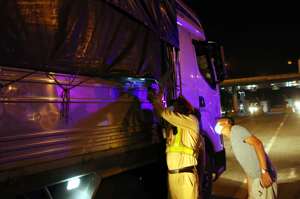 Lực lượng cảnh sát giao thông kiểm tra hàng hóa trên các phương tiện giao thông, nếu chở hàng hóa thiết yếu, nguyên nhiên vật liệu phục vụ sản xuất mới được vào Thủ đô. (Ảnh: Phạm Kiên/TTXVN)