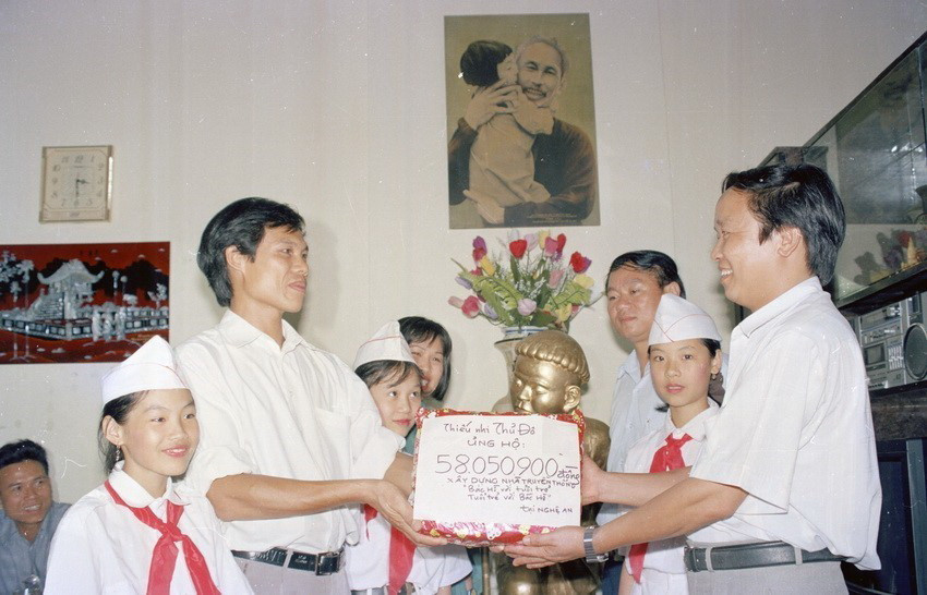 Đại diện Hội đồng Đội Hà Nội trao hiện vật và tiền quyên góp của thiếu nhi Thủ đô ủng hộ phong trào ''Những viên gạch hồng xây dựng nhà truyền thống Bác Hồ với tuổi trẻ, tuổi trẻ với Bác Hồ'' cho tỉnh đoàn Nghệ An (1996). (Ảnh: Đình Trân/TTXVN)