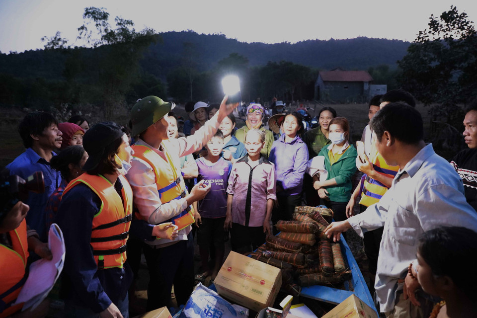 Lực lượng chức năng huyện Minh Hóa, tỉnh Quảng Bình, hướng dẫn người dân thôn 5, xã Tân Hóa, bị cô lập sử dụng đèn tích điện khi chưa có điện lưới. (Ảnh: TTXVN)