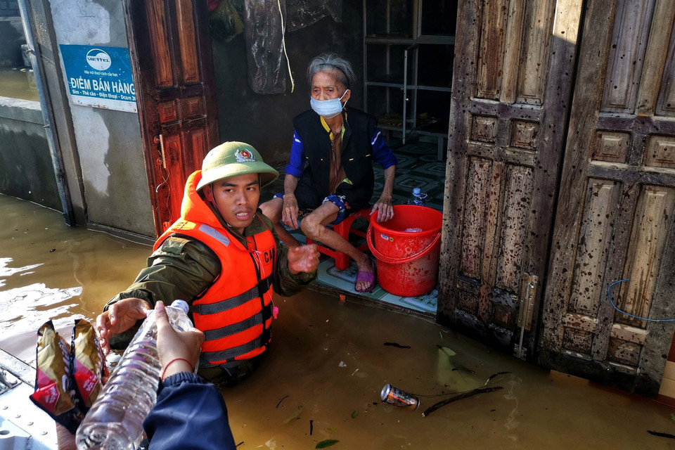 Trung úy Hoàng Trung, Công an huyện Lệ Thủy, lội nước đưa hàng cứu trợ đến mế già. (Ảnh: TTXVN)