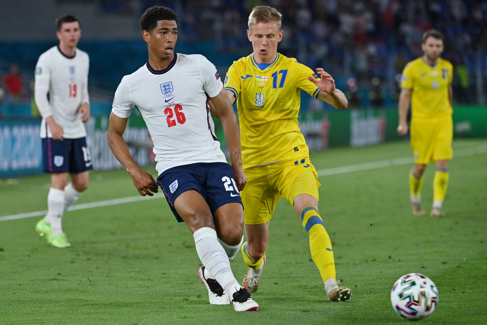 Pha tranh bóng giữa tiền vệ Anh Jude Bellingham (trái) và hậu vệ Ukraine Oleksandr Zinchenko. (Ảnh: AFP/TTXVN)