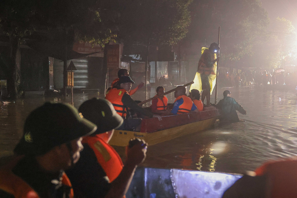 Cán bộ, chiến sỹ Lữ đoàn 210 hỗ trợ đưa người dân ra khỏi những vùng đang bị ngập sâu trong nước. (Ảnh: Hoàng Hiếu/TTXVN)