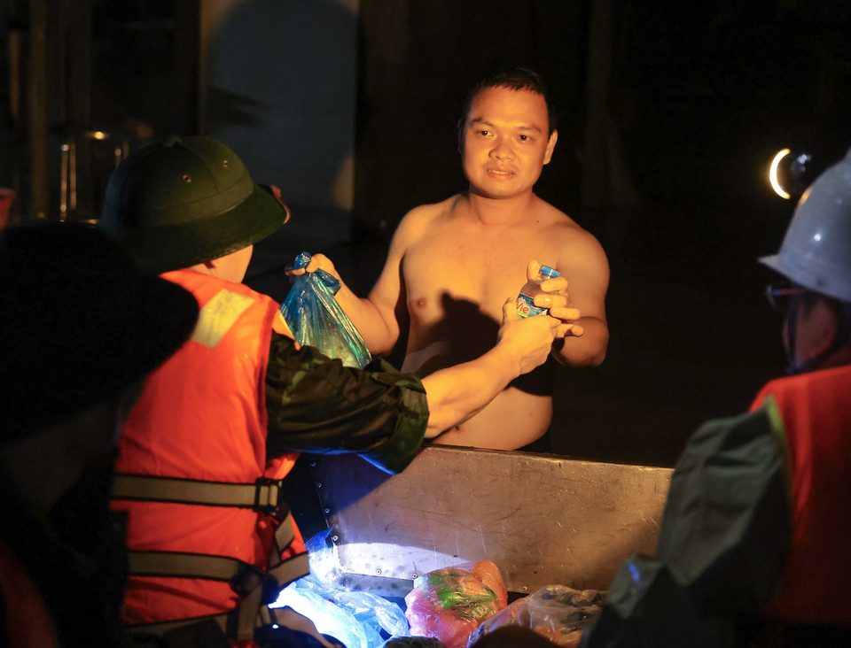 Lương thực, nước uống được cán bộ, chiến sỹ Lữ đoàn 210 đưa đến tận tay người dân bị cô lập do nước lũ. (Ảnh: Hoàng Hiếu/TTXVN)