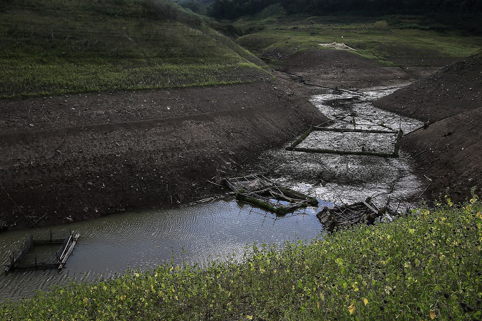 Nắng nóng thiêu đốt kéo dài cả mấy tháng mùa Hè, nước hồ tại các nhánh về huyện Đà Bắc, Tân Lạc, Mai Châu rút đi nhiều làm hồ cạn trơ đáy. Trong ảnh: Một nhánh sông Đà bị cạn nước và những lồng cá của người dân bị mặc kẹt lại trên vùng đất cạn ở xã Tiền Phong, huyện Đà Bắc. (Ảnh: Trọng Đạt/TTXVN)