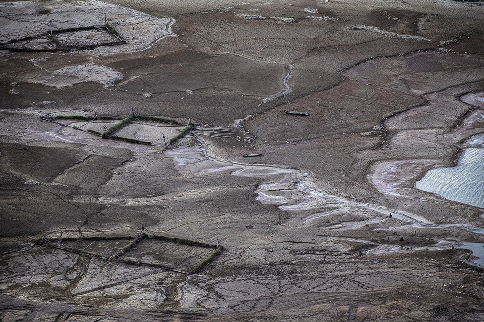 Tình trạng thiếu hụt nước nghiêm trọng của hồ Hòa Bình kéo dài nhiều năm qua. Điều này đã tác động tiêu cực đến hệ sinh thái tự nhiên của dòng sông và sinh kế của người dân trên vùng lòng hồ. Trong ảnh: Những bè cá lồng của người dân không kịp di dời bị mắc cạn lại ngay trên vùng đất mà trước đó còn ngập nước có độ sâu khoảng hơn 10m. (Ảnh: Trọng Đạt/TTXVN)