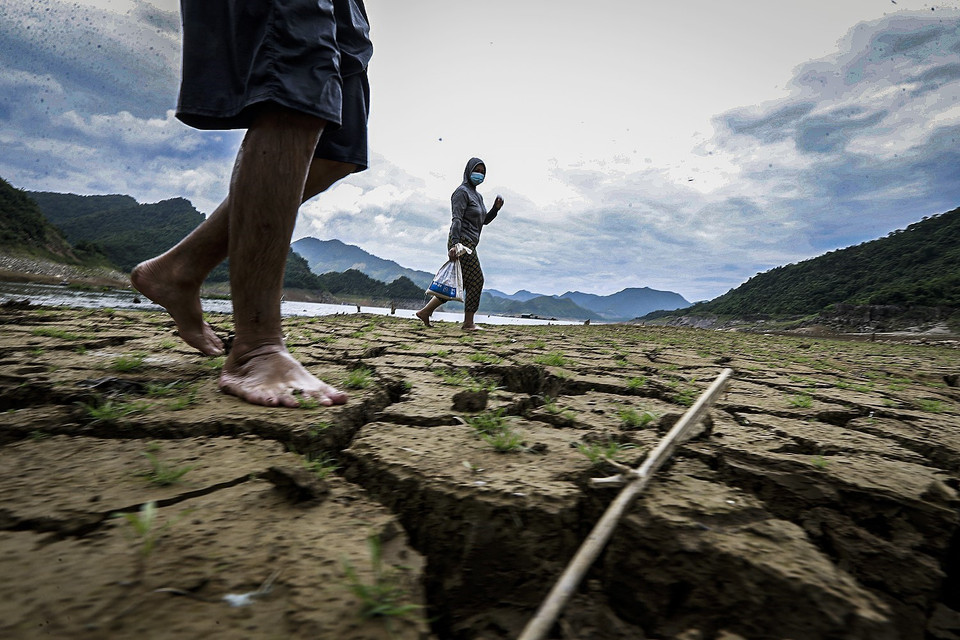 Cuộc sống của người dân và sự toàn vẹn của hệ sinh thái tự nhiên vùng lòng hồ Hòa Bình rồi sẽ ra sao khi sinh kế của nhiều hộ gia đình đang gắn chặt với vùng hồ. Trong ảnh: Người dân xã Hiền Lương, huyện Đà Bắc đi làm về và băng tắt ngay trên lòng sông Đà bị cạn nước và nứt nẻ. (Ảnh: Trọng Đạt/TTXVN)
