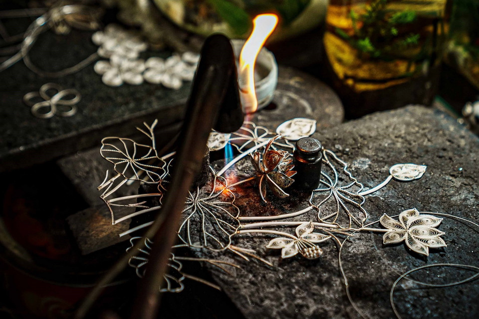 Bức tranh hoa sen với nhiều chi tiết, hoa văn nhỏ đang được người thợ kim hoàn Định Công đấu (hàn). (Ảnh: Phạm Tuấn Anh/TTXVN)