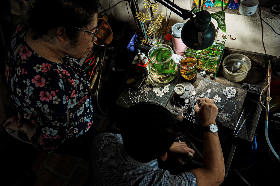 Những người thợ bạc Định Công chế tác bức tranh hoa sen - một "bức tranh" qua nhiều công đoạn thường mất nhiều ngày mới chế tác xong. (Ảnh: Phạm Tuấn Anh/TTXVN)