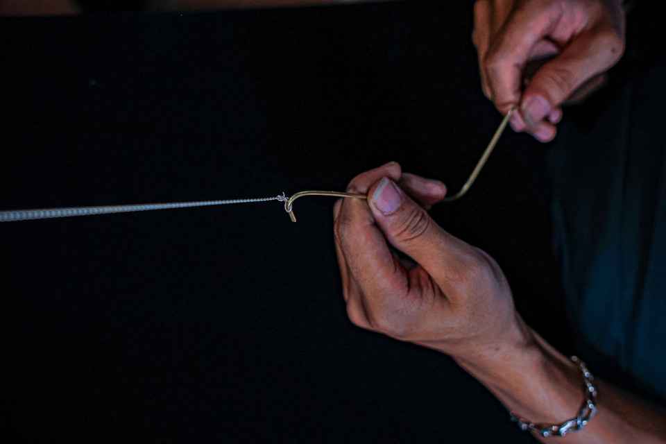 Từ sợi bạc nhỏ như sợi tóc, người thợ quay, đan, ghép 2 sợi thành một. (Ảnh: Hoàng Hiếu/TTXVN)