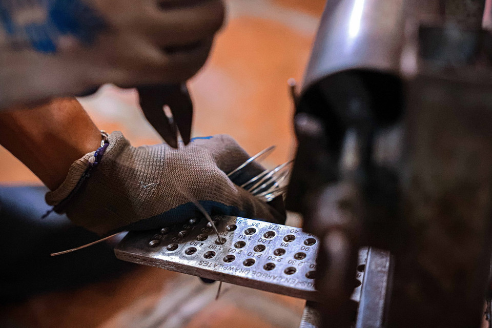 Bạc được những người thợ Định Công kéo thành những sợi mảnh như sợi tóc, sau đó qua 4 công đoạn trơn, đấu (hàn), chạm, đậu, thành sản phẩm đậu bạc Định Công. (Ảnh: Hoàng Hiếu/TTXVN)