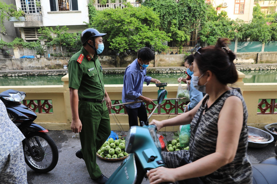 Công an phường nhắc nhở người dân cần tuân thủ đúng quy định phòng dịch. (Ảnh: Thành Đạt/TTXVN)
