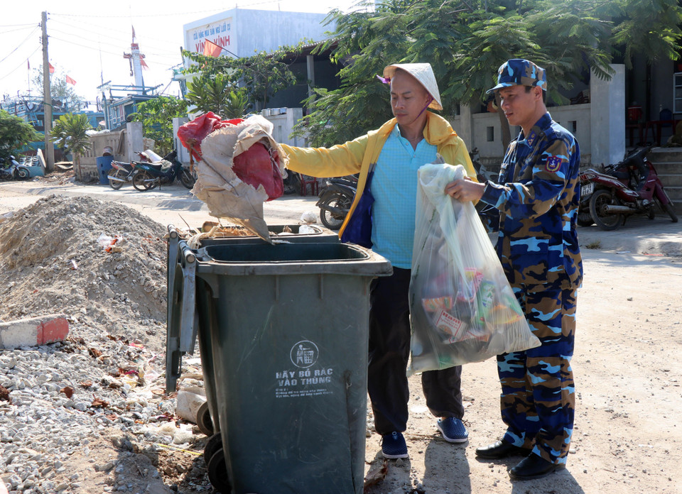 Chiến sỹ Vùng cảnh sát biển 2 phối hợp với thanh niên tình nguyện dọn vệ sinh môi trường biển tại huyện đảo Lý Sơn, Quảng Ngãi. (Ảnh: Trần Tĩnh/TTXVN)